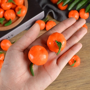 Realistic mini PVC orange model with green stem held in hand for dollhouse decoration
