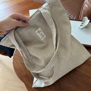 Détail du cabas en toile beige avec tissu texturé et étiquette de marque décorative et arty