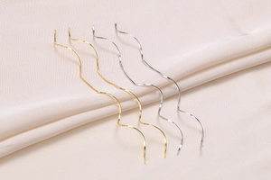 Detail of elegant gold and silver long wavy threader earrings on white silk fabric