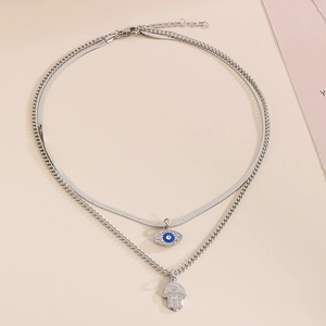 Detail of silver double-layered necklace with blue enamel evil eye and hamsa hand charms