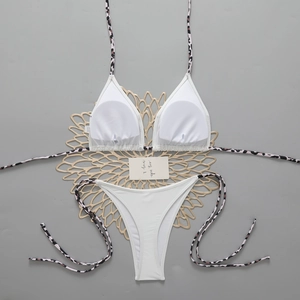 Flat lay of white bikini top and bottom with leopard print straps and gold mesh detail
