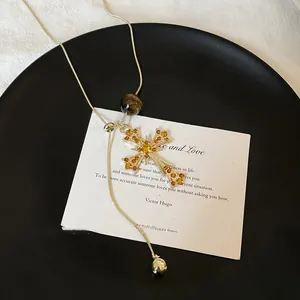 Detail of tiger eye stone cross pendant necklace on snake chain with golden accents