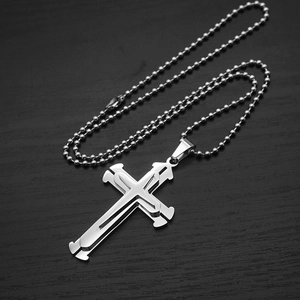Close-up of a silver triple-layered cross pendant with bead chain on wood background