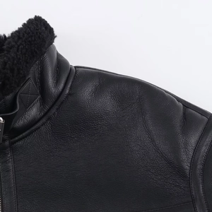 Detailed macro view of black leather jacket shoulder seams and plush fleece collar texture