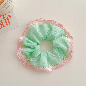 Close-up of mint green scrunchie with pink and white floral crochet lace trim