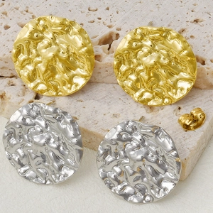 Detail of gold and silver irregular pleated stud earrings on a stone display