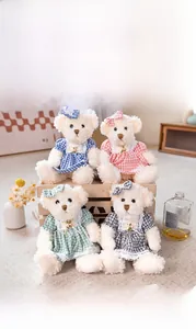 Close-up of four plush teddy bears in plaid dresses with floral details on a wooden crate