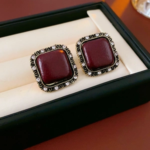 Macro di orecchini a perno rossi vintage con bordo dorato e cristalli brillanti