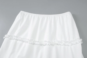 Detail view of the elastic waist and ruffled tier design on a white summer maxi skirt