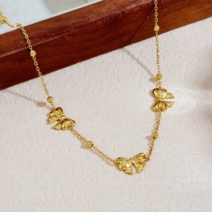 Minimalist gold plated stainless steel bead chain necklace with bow pendants on wooden background