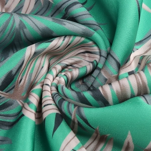 Macro detail of tropical palm leaf print on silky satin fabric with elegant drape