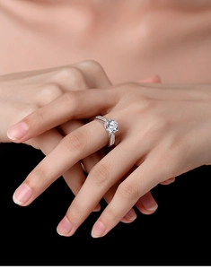 Classic six-prong round moissanite ring with pavé diamonds on finger on dark background