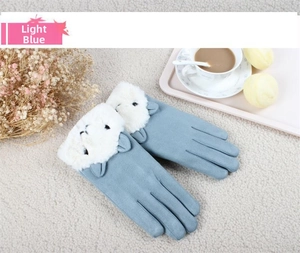 Macro detail of pale blue suede gloves featuring cute sheep embroidery and faux fur trim