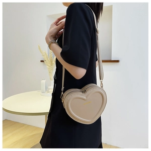 Dettaglio della borsa a tracolla beige a cuore con motivo trapuntato e zip dorate