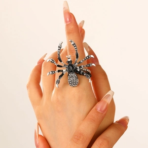 Punk style large silver spider ring with black crystals on finger, 45-degree angle view