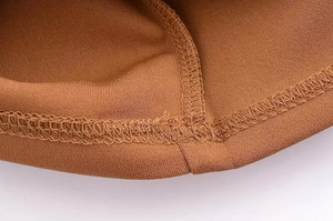Close-up of brown knitted fabric detail showing high-quality stitching on the dress