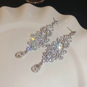 Macro detail of silver teardrop earrings with crystals and vintage hollow engravings