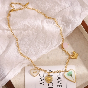 Detailed view of 18K gold-plated necklace with dried flower heart and butterfly charms