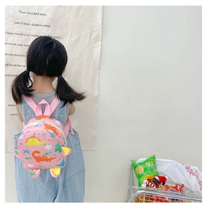 Pink toddler backpack with colorful cartoon dinosaur patterns worn by a small child