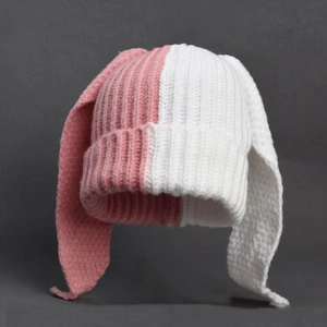 Close-up of pink and white color block knit hat featuring long rabbit ear details