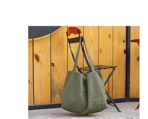 Minimalist green canvas tote bag on black chair showing material and shoulder strap