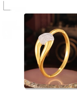 Detailed shot of interlocking gold bangle featuring a pavé-set shimmering zircon panel