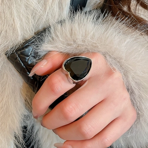 Detail of a luxury silver-toned ring featuring a large black heart-shaped zircon stone