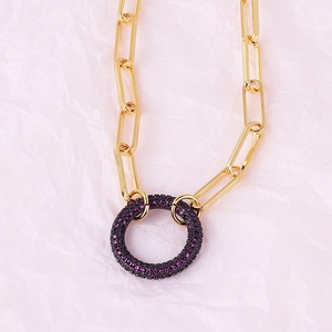 Detailed view of a gold paperclip chain necklace with a purple stone encrusted circle pendant