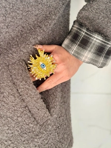 Detalle de un brazalete ancho dorado con diseño de ojo turco y cristales brillantes