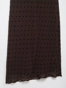 Detail of dark brown sheer fabric with black flocked polka dots and ruffle hemline