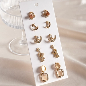 Detail of 5-pair gold stud earring set featuring heart pearl, crescent moon and star charms