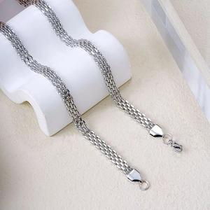 Silver woven mesh chain necklace with lobster clasp on a minimalist display stand