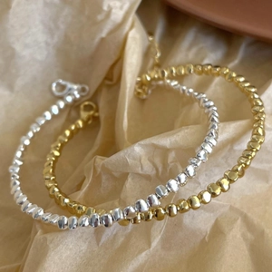 Detail of minimalist S925 silver and gold bracelets with irregular stone-shaped beads