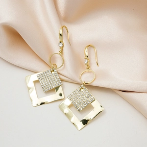 Detail of gold geometric square earrings with sparkling white cubic zirconia on silk