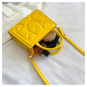 Vue intérieure du mini sac jaune gaufré cœurs montrant l'espace pour parfum et maquillage