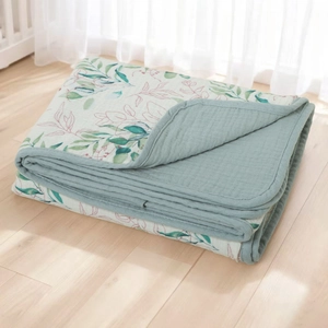 Detailed close-up of double-sided cotton baby blanket with green leaf pattern on wood