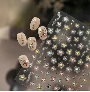 Macro detail of 3D floral nail stickers with pearl accents and silver ribbons on soft pink nails