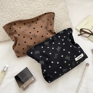 Dettaglio di pochette trucco in velluto a coste con stampe di cuori e fiocchi chic