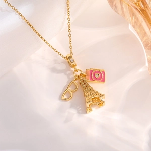 Gold fashion necklace with Eiffel Tower, pink camera, and glasses charms on satin
