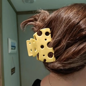 Detailed view of creative yellow cheese shaped hair claw clip styled in a ponytail