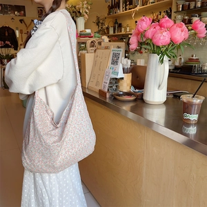 Detail of floral canvas hobo bag with wide shoulder strap in a cozy cafe setting