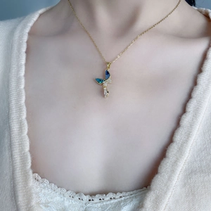Close-up of golden butterfly pendant with blue gradient shell and small crystals on a neck