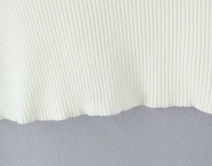 Dettaglio macro del tessuto a maglia a coste bianche con trama e bordo ondulato del set