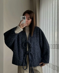 Detail of loose dark grey mohair cardigan with lace-up front and fuzzy texture