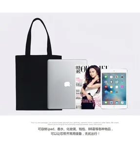 Black canvas tote bag showing capacity with 13-inch laptop and A4 magazine items