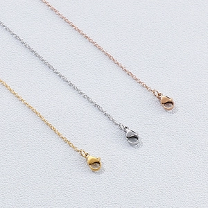 Vue détaillée des fermoirs mousquetons sur colliers en acier or, argent et rose doré