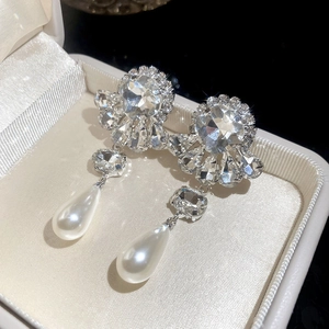Detail of flower-shaped crystal earrings with teardrop pearls in a jewelry box