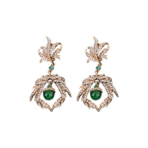 Vintage gold leaf earrings with green gems and rhinestones on a white background