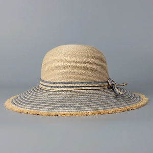 Detailed view of raffia sun hat with raw edges and striped decorative bow band
