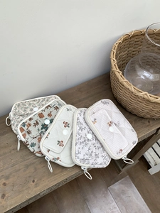 Detail of five quilted cotton mini pouches with floral patterns on a rustic wooden bench